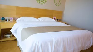 Habitación de hotel con cama doble, cabecera de madera, mesita de noche con teléfono y una pequeña mesa, y una pared con diseños circulares.