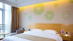 Habitación de hotel con una cama grande, cabecera de madera, mesita de noche con teléfono y una pared con diseños circulares.