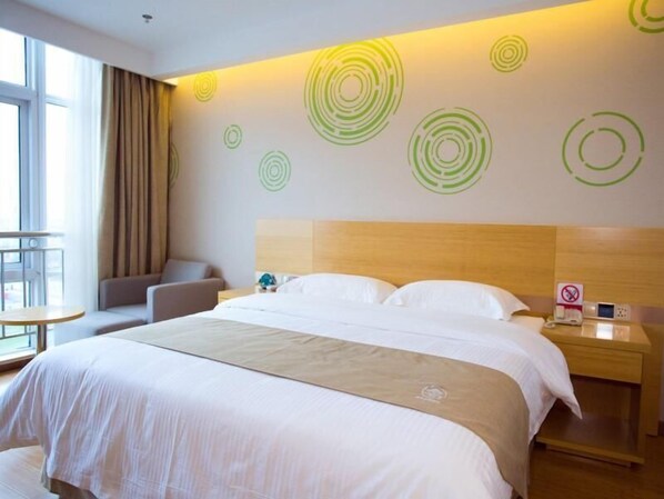 A hotel room with a large bed, a wooden headboard, a bedside table with a phone, and a wall with circular patterns.