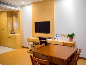 A modern hotel room with a wooden desk, a flat-screen TV, a dining table, and a potted plant. - Greentree Inn Nantong Rugao Jiangan Town Xinjiangan Square (Nantong)