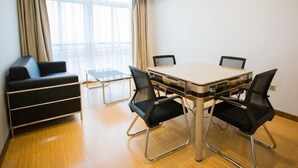 Un salón de conferencias con una mesa grande, cuatro sillas, un sofá y una ventana con cortinas.