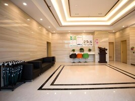 A modern lobby with a marble floor, black and white patterned carpet, and a reception desk with colorful chairs.