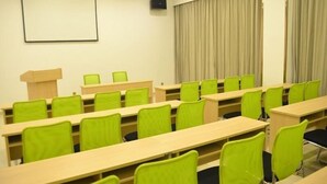 A conference room with rows of green chairs and beige tables, a projector screen, and a curtain on the window. - Greentree Inn Suzhou Changshu Huanghe Road Linli C (Suzhou)