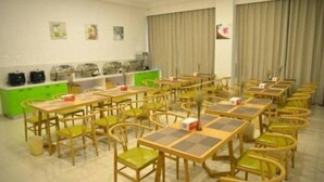 A dining area with multiple tables and chairs, a counter with food items, and a large window with curtains. - Greentree Inn Suzhou Changshu Huanghe Road Linli C (Suzhou)