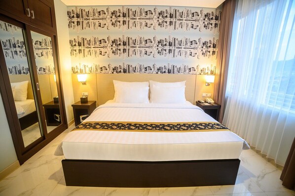 A hotel room with a large bed, a mirror, two bedside tables with lamps, and a cityscape wallpaper.