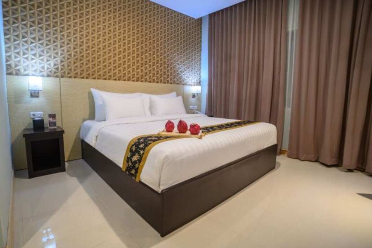 Une chambre d’hôtel avec un grand lit, une table de chevet et un mur orné d’un motif.