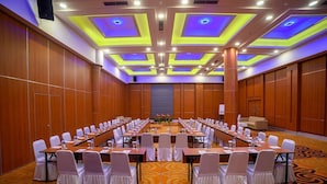 A conference room with long tables, white chairs, and a carpeted floor.