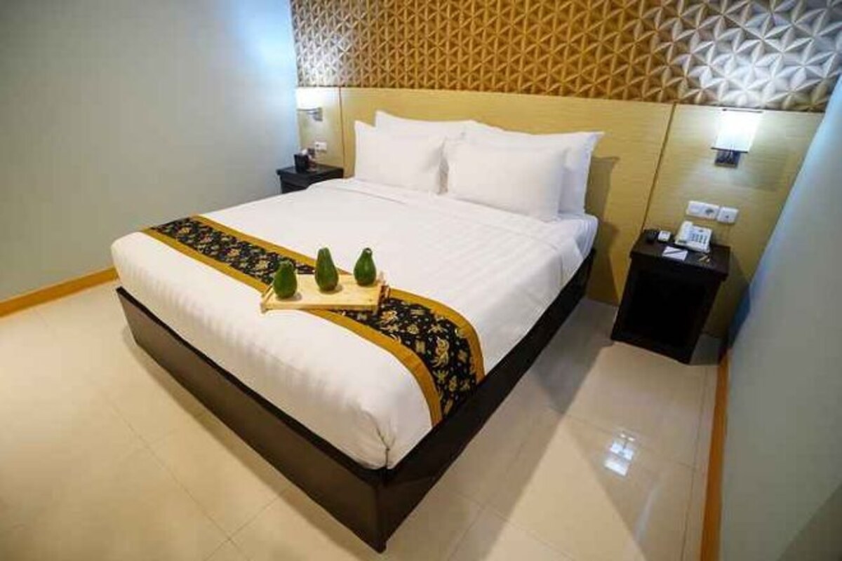 Une chambre d’hôtel avec un lit, des tables de chevet et un mur orné d’un motif.