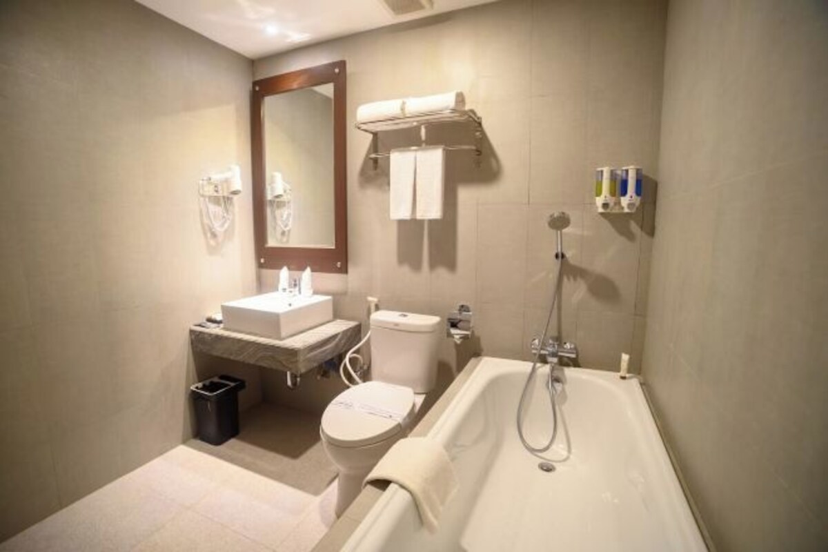 Une salle de bain équipée d’une baignoire, de toilettes, d’un lavabo et d’un miroir.