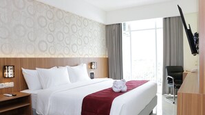 Una habitación de hotel con cama, mesita de noche, lámpara y escritorio con silla.