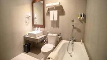Une salle de bain comprenant des toilettes, un lavabo, un miroir, un porte-serviettes et une baignoire.