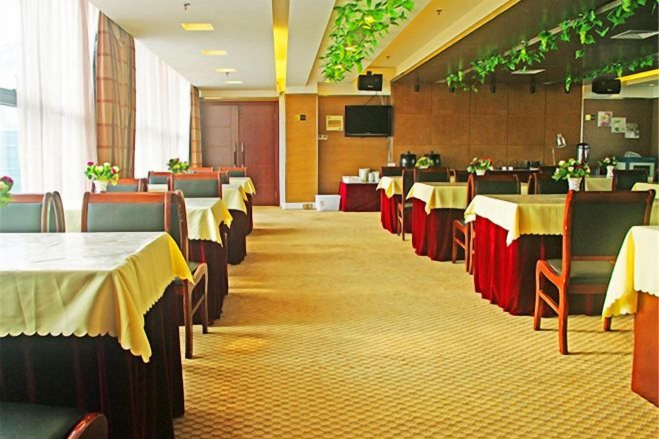 A hotel dining area with multiple tables, chairs, and a carpeted floor.