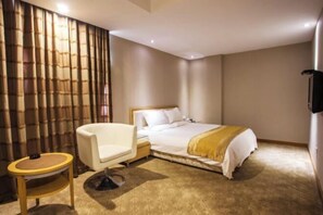 Una camera d'albergo con un letto, una sedia, un comodino e una tenda.
