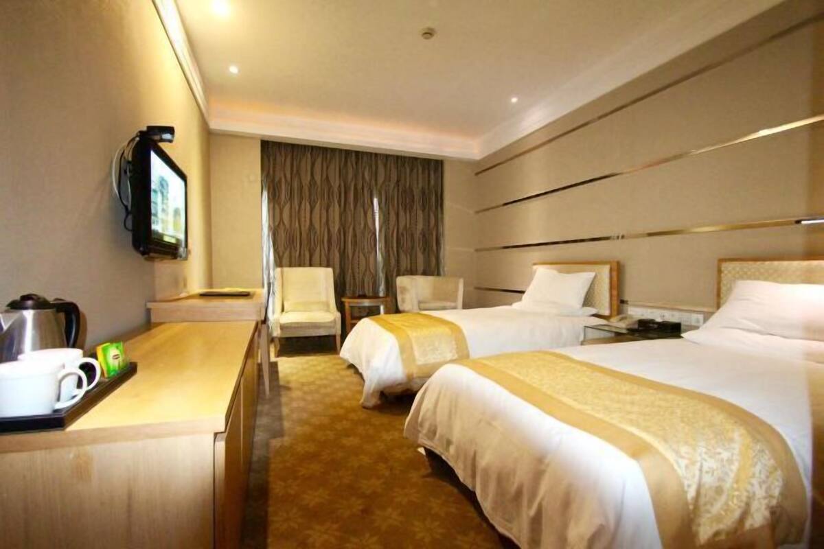Une chambre d’hôtel avec deux lits, un bureau, une télévision et un coin salon.