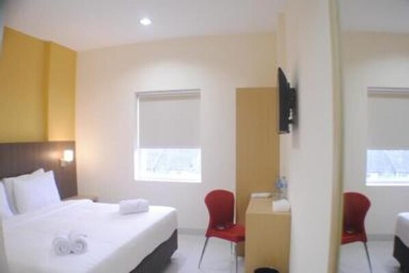 A hotel room with a bed, a desk, a chair, and a television. - Astera Hotel Bintaro (Ciputat)