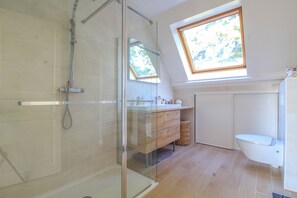Een bad/douchecombinatie, een haardroger, handdoeken, toiletpapier