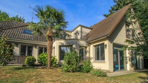 Une maison à deux étages, avec un toit en tuiles, de grandes fenêtres et une pelouse bien entretenue.