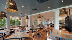 A spacious restaurant with high ceilings, wicker pendant lighting, and a mix of wooden and upholstered tables and chairs. - Hotel Excelsior (Golden Sands)