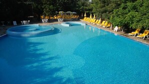 A large, clear swimming pool with yellow lounge chairs and tables around it. - Hotel Excelsior (Golden Sands)