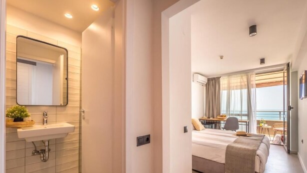 A modern hotel room with a bathroom, a bed, a balcony, and a view of the sea. - Hotel Excelsior (Golden Sands)