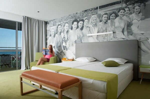 A hotel room with a large bed, a bench, a desk, and a large window. - Hotel Excelsior (Golden Sands)