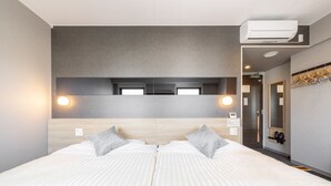 Una habitación de hotel moderna con una cama grande, un espejo y un equipo de aire acondicionado.