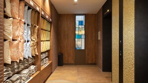 Un pasillo con suelo de madera, una puerta de cristal y una pared con textura.