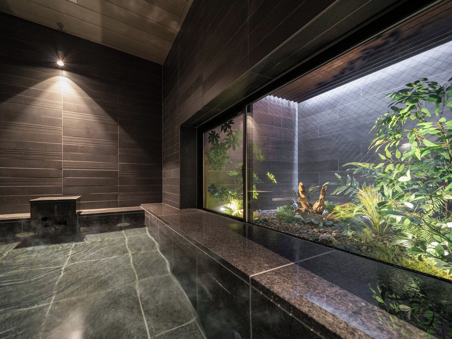 A modern bathroom with a large window, a heated floor, and a small seating area.