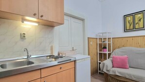 A compact kitchen with wooden cabinets, a built-in sink, and a white refrigerator. - Heart of the Town (Dubrovnik)