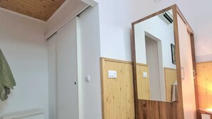 A room with a wooden ceiling, white walls, a wooden door, a mirror, and a radiator. - Heart of the Town (Dubrovnik)