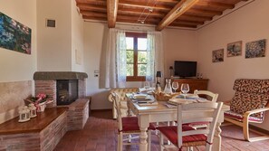 A dining area with a fireplace, a television, and a patterned sofa. - Casetta Di Petriolo, Cerreto Guidi, Florence and Chianti (Cerreto Guidi)