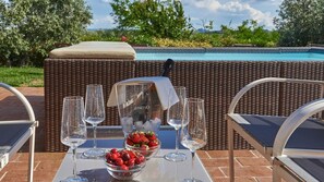 Une table dressée avec des verres à vin, une bouteille de vin Mionetto et un saladier rempli de fraises et de cerises.