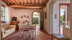 A cozy living room with a leather sofa, dining table set for four, and a TV on a wooden cabinet. - Casetta Di Petriolo, Cerreto Guidi, Florence and Chianti (Cerreto Guidi)