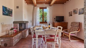 Un coin repas chaleureux avec une cheminée en briques, un téléviseur et un fauteuil confortable.