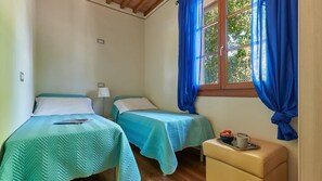 A room with two beds, a window with curtains, a bedside lamp, and a small table with a bowl and mug. - Casetta Di Petriolo, Cerreto Guidi, Florence and Chianti (Cerreto Guidi)