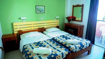 Una cama doble con cabecera de madera, dos mesitas de noche, un espejo y una ventana con cortinas.