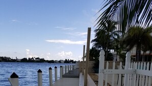 A wooden boardwalk leading to a beach with white railings and palm trees. - Fisherman's Paradise (Marathon)