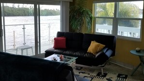 A living room with a black sofa, a glass coffee table, and a view of a body of water through large windows. - Fisherman's Paradise (Marathon)