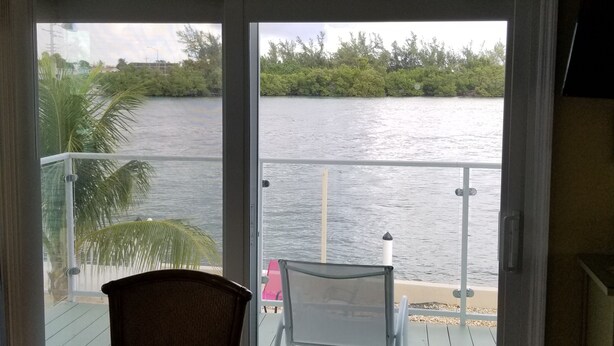 A room with a view of a body of water, a ceiling fan, and a table with chairs. - Fisherman's Paradise (Marathon)