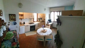 Cuina compacta amb zona de menjador, que inclou una placa de cocció, un rentaplat i una taula petita amb cadires.