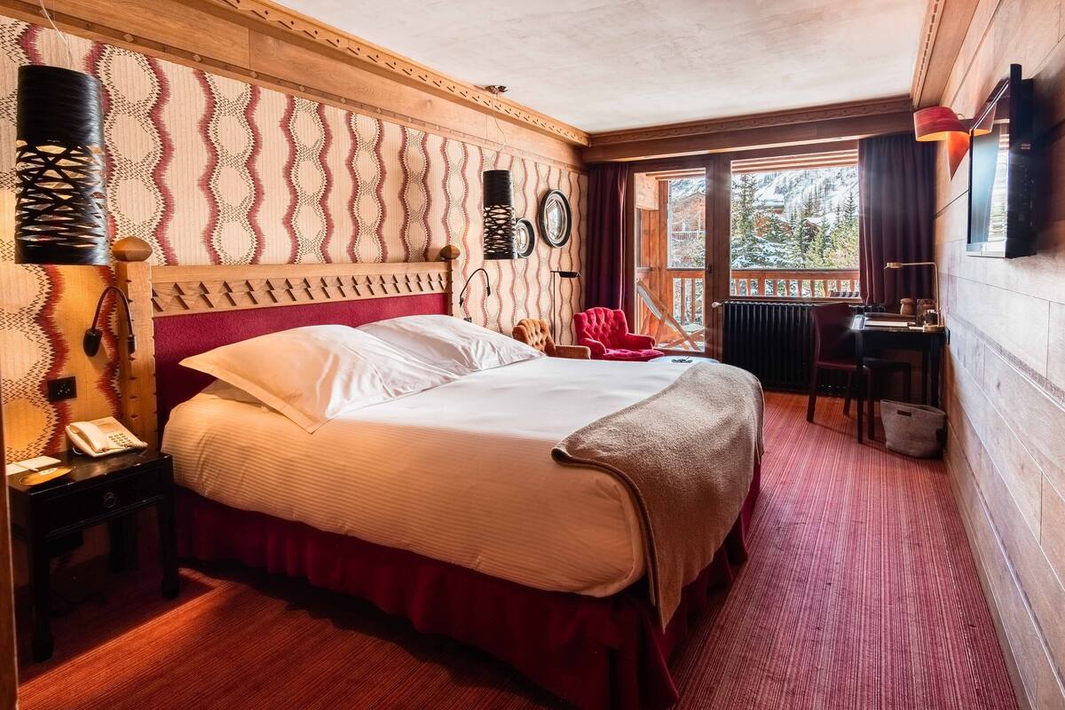 A wooden-paneled bedroom with a bed, a desk, and a chair.