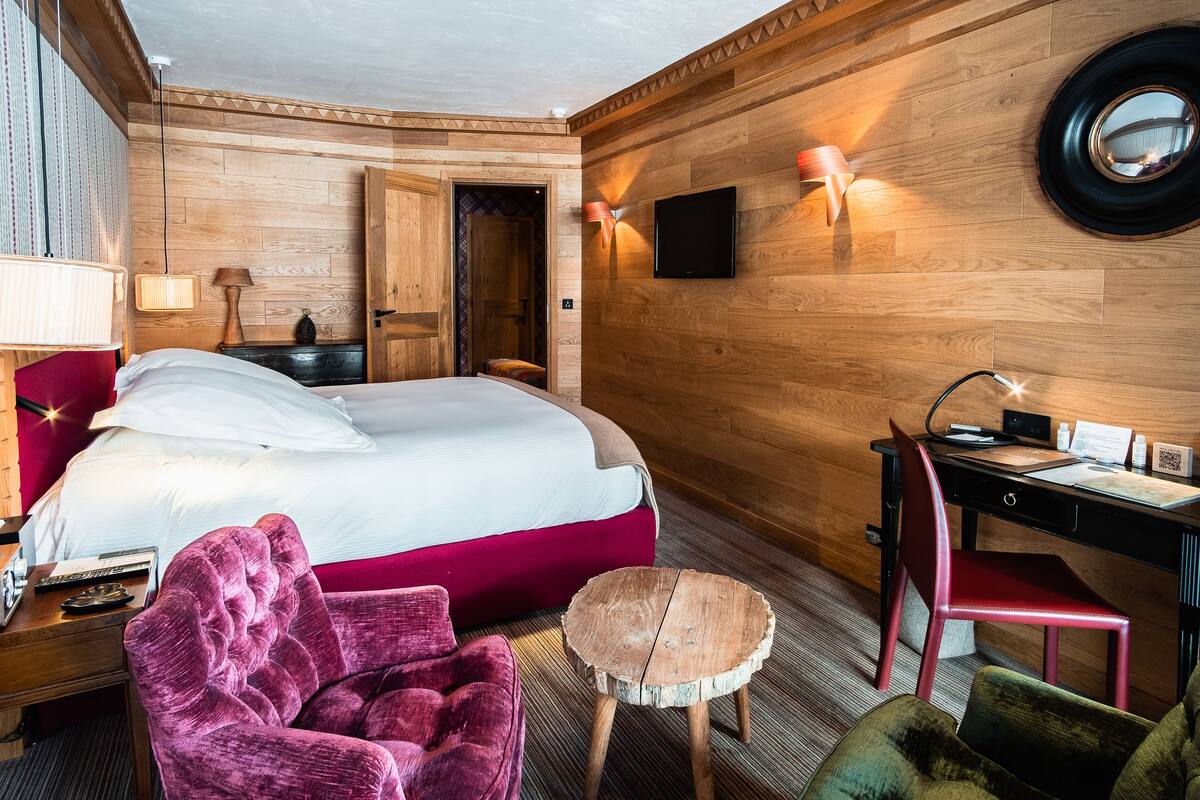 A hotel room with a bed, a desk, a chair, and a small round table.