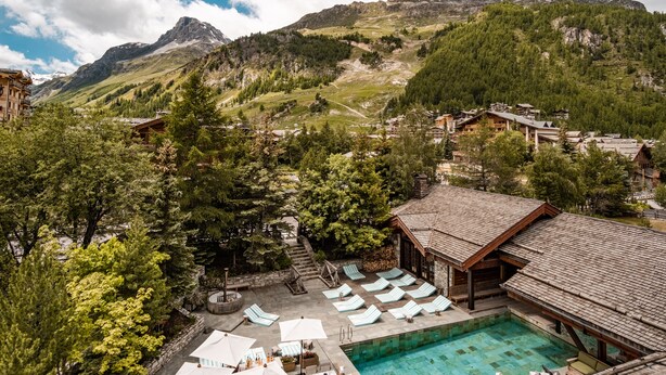 Un complexe hôtelier doté d'une piscine, d'un espace extérieur aménagé et offrant une vue sur les montagnes.