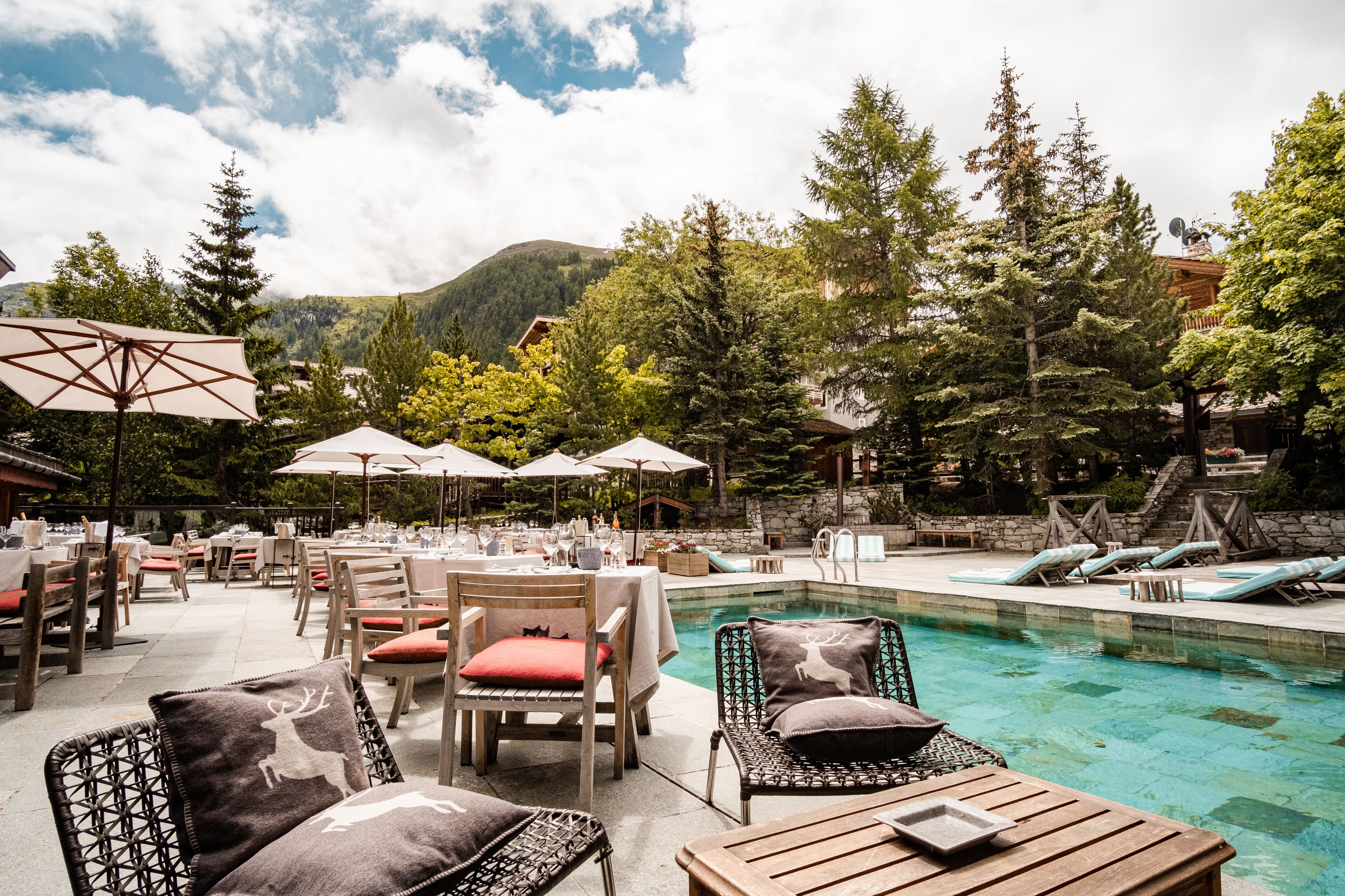 Un espace extérieur avec piscine, comprenant des chaises longues, des parasols et des tables à manger, aménagé pour le confort des clients.