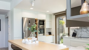A modern kitchen with a central island, built-in appliances, and a view to the outdoors. - Lagoon Seaside Villa, Walking distance to the beach & shops!Car Free holiday! (Panormos in Rethymno)