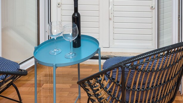 Un balcon avec une table, deux chaises et une bouteille de vin.