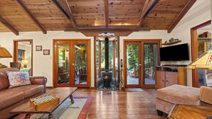 A wooden-floored living room with a fireplace, a television, and a sofa.