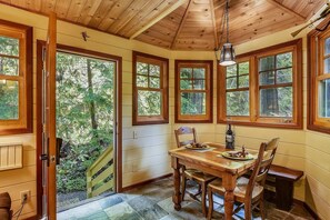 A cozy cabin with a wooden interior, large windows, and a dining area with a table and chairs.