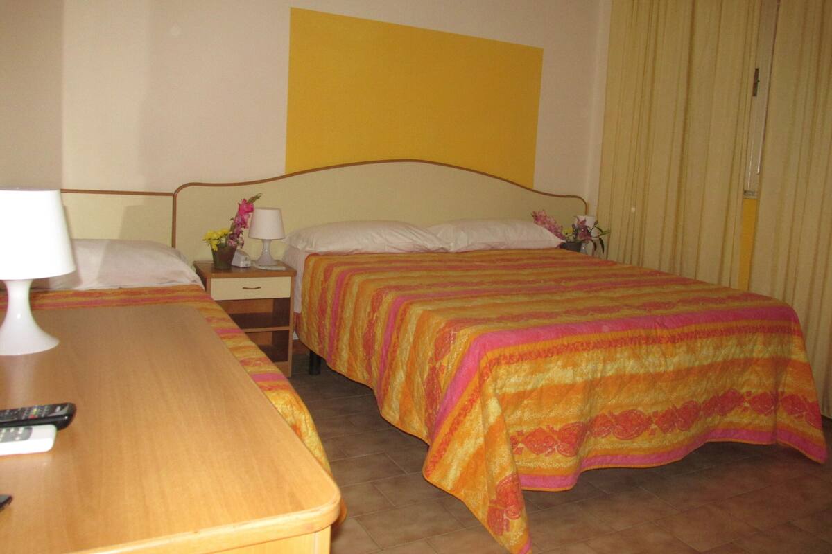 Una habitación de hotel con cama, mesita de noche, lámpara y una mesa de madera.