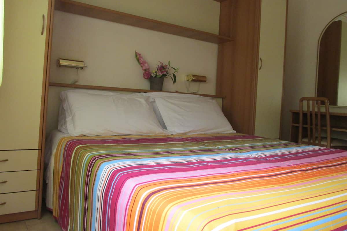 Un dormitorio con cama, mesita de noche, silla y escritorio.